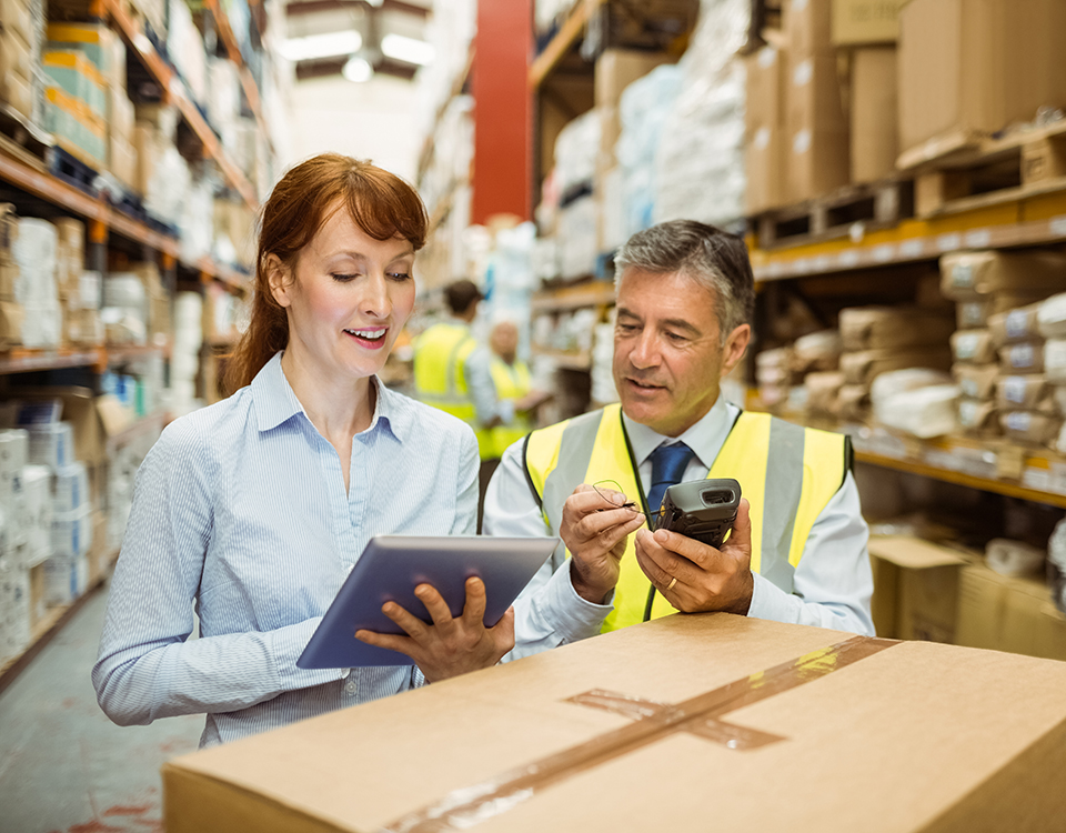 Warehouse managers looking at tablet pc in a large warehouse