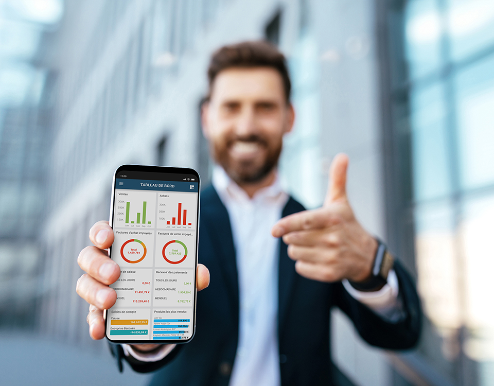 Smiling european young bearded businessman in suit rejoices to success and points finger at smartphone