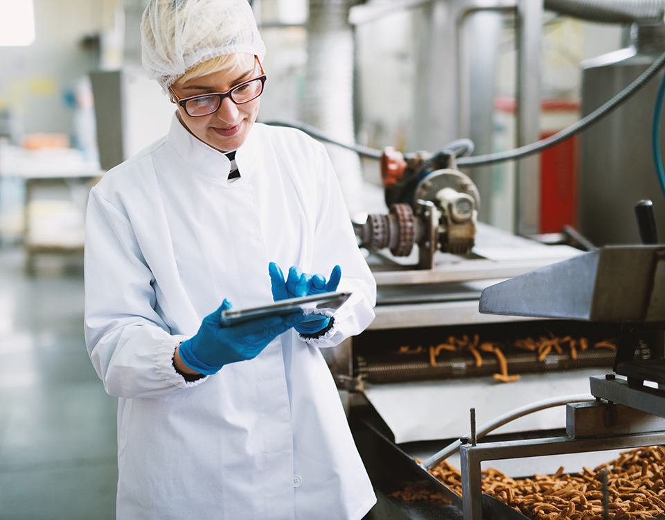 Young female worker in sterile clothes is checking quality of pr